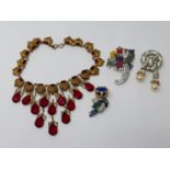 A Trump tower gilt metal and red crystal necklace together with three costume brooches one by