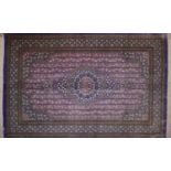 A Qum silk rug with central floral medallion, on a purple ground, contained by floral motifs and