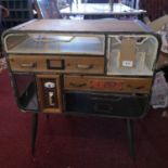 An industrial style wood and metal side chest with an assortment of drawers raised on dansette