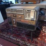 An industrial design metal cabinet with an arrangement of wood and mesh drawers raised on dansette