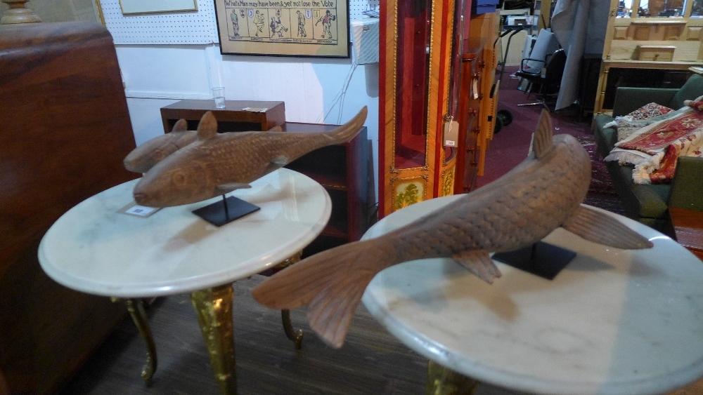 A set of three carved wooden fish on stands (3)