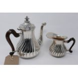 A Continental silver tea pot with floral finial, having wooden handle, together with a matching milk