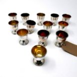 A collection of 13 silver egg cups, with gilt interiors, on spreading feet, by Angora Silver Plate