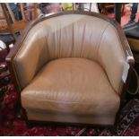 An Art Deco style tub armchair with an oak show frame and soft tan leather upholstery