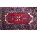 A Persian carpet with floral diamond medallion, on a red and blue ground, contained by geometric