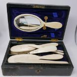 A late 19th century ivory vanity set, to include a mirror (glass cracked), a shoe horn with button