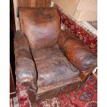 A 1930's French club armchair, with studded worn tan leather upholstery raised on hoof block
