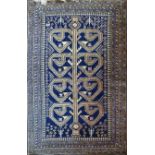 An Afghan rug, the central golden design on a midnight blue ground within multiple geometric