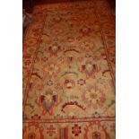 A Liberty style large woolen carpet with central floral motifs on a green ground, contained by