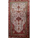 A Persian silk rug, the central tree of life design on an ivory ground within a ruby border with
