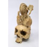 A late 19th century Japanese carved netsuke depicting a large skull topped with a rooster and