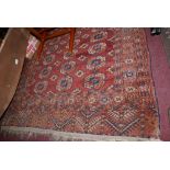 A Persian Bokhara carpet, elephant pad motifs on a rouge ground, within geometric borders,