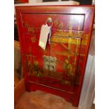 An Oriental red lacquered side cabinet with single drawer over cupboard doors with gilt painted