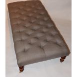 A contemporary footstool, with deep buttoned grey linen upholstery over turned supports, H.33cm L.