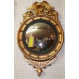 A Regency style giltwood mirror, the circular convex mirror within ebonised border, having eagle and