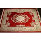 A 20th century Chinese woolen carpet with floral medallion on a red ground contained by floral