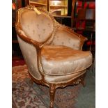 A pair of Louis XV style giltwood armchairs, with golden silk upholstery, raised on cabriole legs