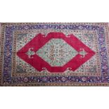 A North West Persian Tabriz carpet, central diamond medallion on a rouge field within stylised