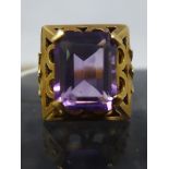 An Art Deco 14ct yellow gold and amethyst ring, centrally four claw-set with a stepped-cut,