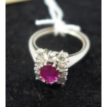 An 18ct white gold, natural ruby and diamond cluster ring, the central oval faceted ruby in a six-