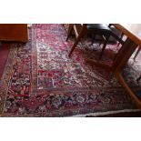 An antique Heriz carpet with central geometric medallion, on a red and cream ground, contained by