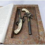 A pair of reproduction flintlock pistols enclosed in a hollowed out antique French encyclopedia