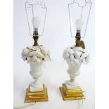 A pair of 20th century white ceramic table lamps in the form of urns of fruit, raised on giltwood