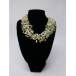 A multi-strand collar necklace composed of white and pink freshwater pearls and peridot beads,