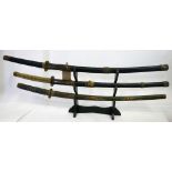 Three early 20th century Japanese samurai swords, to include one with a green lacquered case, signed
