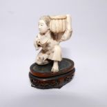 A Meiji period Japanese carved ivory okimono depicting a crouching figure with basket of shells on a