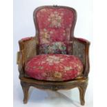 A 19th century carved walnut bergere armchair with double caned sides in rose floral upholstery.