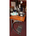 A Willcox & Gibbs overlock sewing machine, set on oak top with a lamp above cast metal supports