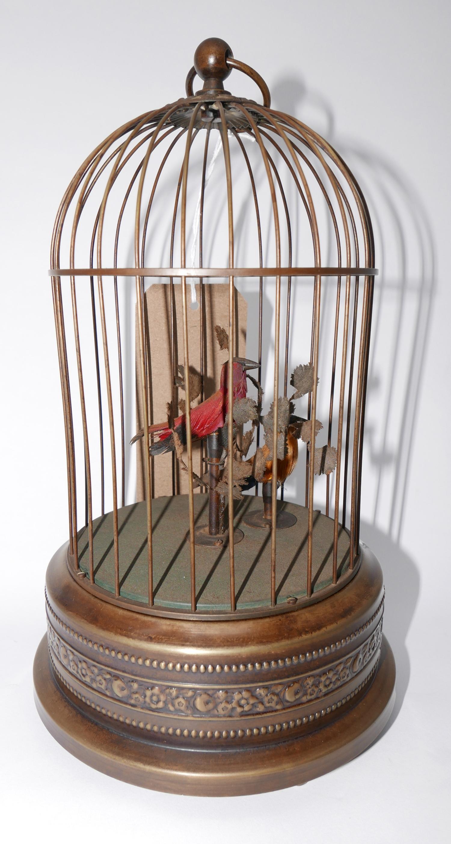 An early 20th century bird cage automoton with yellow and red feathered birds with foliage, on a
