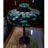 A Tiffany style leaded and stained glass lamp in shades of mottled green with dark red flowers, to a