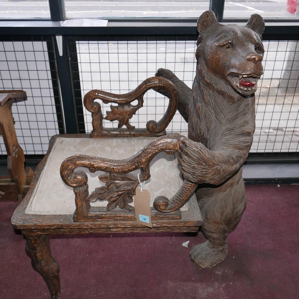 A Black Forest carved armchair with a large bear to the back of the piece and ornate arms adorned