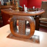 An African hand-carved and decorated stool of stylised circular form with rectangular top and