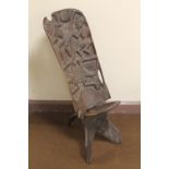 AN AFRICAN CARVED WOOD FOLDING CHAIR, the back carved with dancing figures