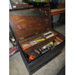 A LARGE WOODEN CHEST CONTAINING TOOLS, PAINT BRUSHES ETC PLUS A SAW HORSE