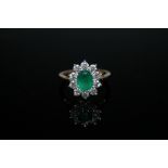 AN 18 CARAT GOLD EMERALD AND DIAMOND RING, the 1.2 carat emerald is surrounded by ten brilliant