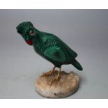 A CARVED MALACHITE MODEL OF A PARAKEET, with glass eyes, gilt finish to legs and feet, raised on a