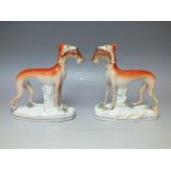 A PAIR OF STAFFORDSHIRE STYLE FLATBACKS IN THE FORM OF STANDING GREYHOUNDS WITH RABBITS, raised on