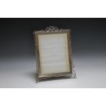 AN ORNATE HALLMARKED SILVER PICTURE FRAME, of rectangular easel back form and having pleasing wire