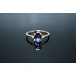 A HALLMARKED 9 CARAT GOLD TANZANITE RING, the oval tanzanite coming with a stone either side and