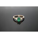 A HALLMARKED 9 CARAT YELLOW GOLD EMERALD RING, set with an oval claw set emerald with a brilliant