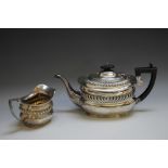 A HALLMARKED SILVER TEAPOT AND CREAM JUG BY GEORGE NATHAN AND RIDLEY HAYES - CHESTER 1911, having