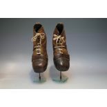 A PAIR OF EARLY 20TH CENTURY LEATHER FOOTBALL BOOTS ON DISPLAY STANDS