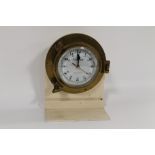 A BRASS PORT HOLE WITH QUARTZ CLOCK MOVEMENT FITTED on homemade stand