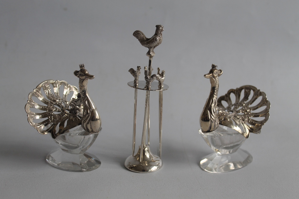 TWO CONTINENTAL WHITE METAL & GLASS SALTS, in the form of peacocks, along with a small plated cockt