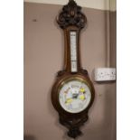 AN EDWARDIAN OAK CARVED ANEROID BAROMETER