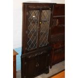 AN OAK CORNER CABINET WITH LEADED GLASS PANELS